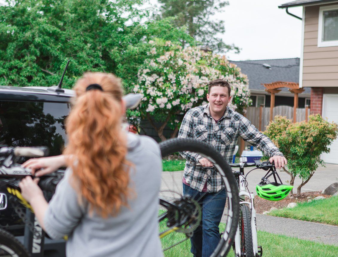 Behind the scenes image from a Spin Creative video production shoot on location in Seattle, for Harborstone Credit Union. The image features a couple loading up a car with mountain bikes, in their front yard.
