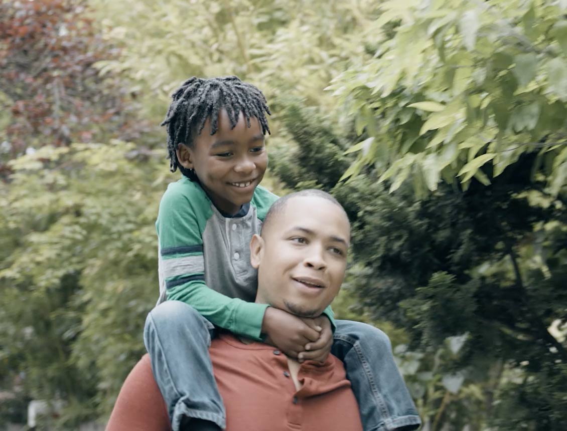 A screen capture from a TV and digital spot for Harborstone Credit Union, part of a campaign created and produced by Spin Creative. The image shows a Dad carrying his Son on his shoulders.