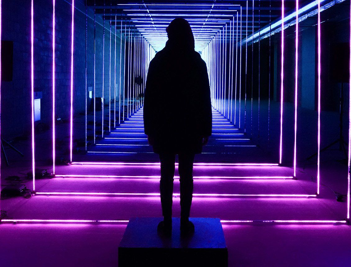 Image of a silhouetted person standing in a purple neon hallway.