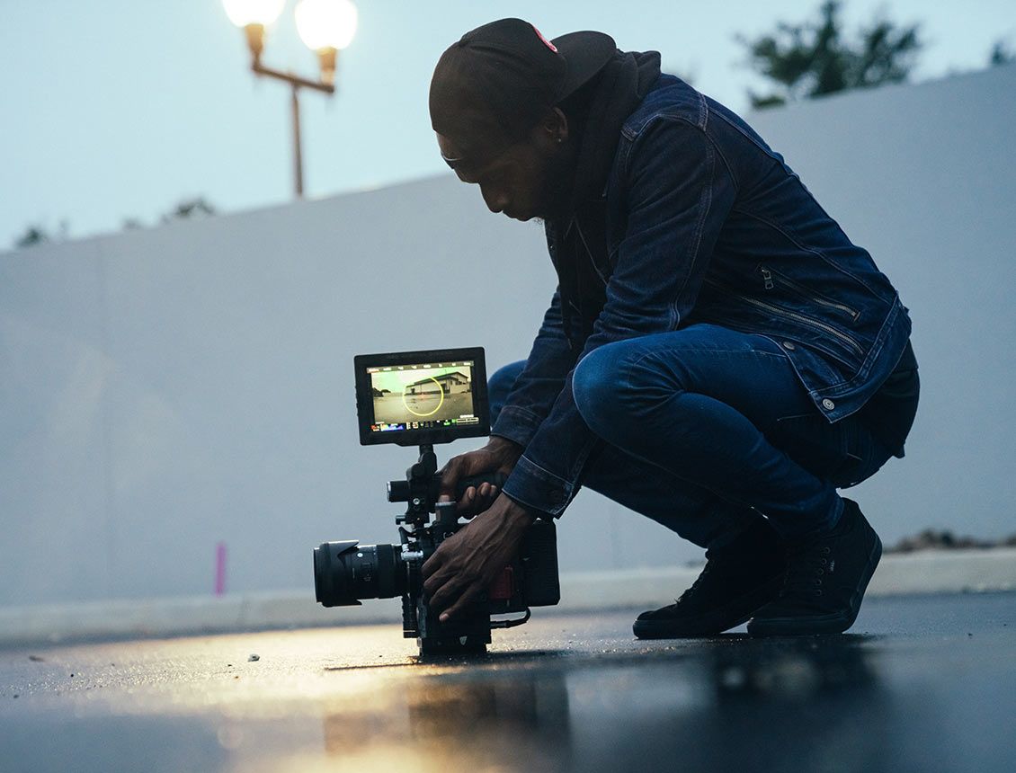 Image of man holding a cinema video camera with monitor on ground