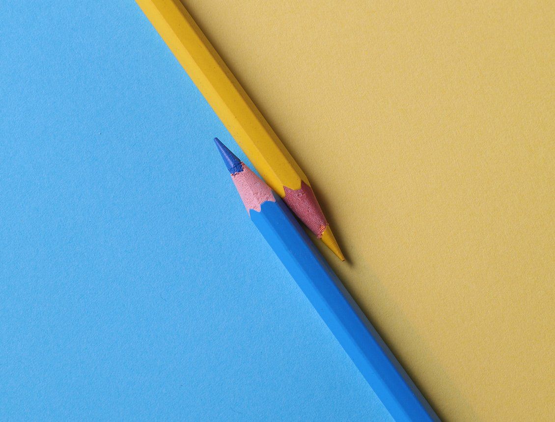 Yellow and blue sharpened pencils on top of blue and yellow backgrounds representative of a creative video production agency