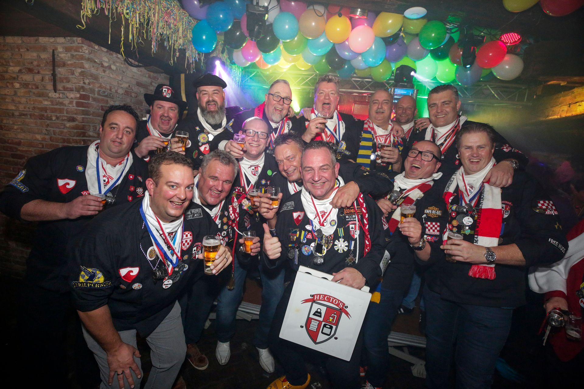 Een groep mensen poseert voor een foto met ballonnen op de achtergrond.