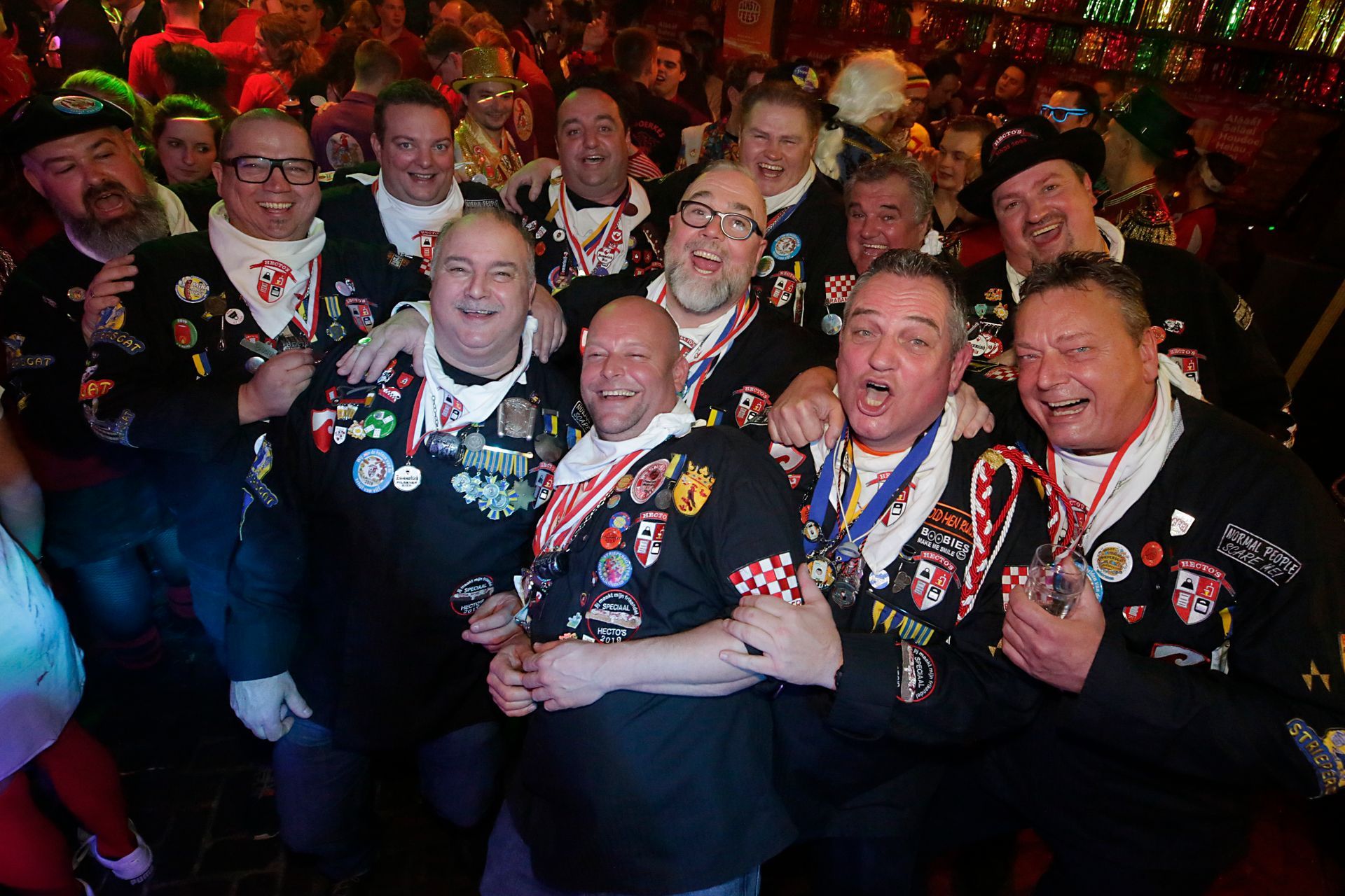 Een groep mannen poseert voor een foto in een drukke kamer.