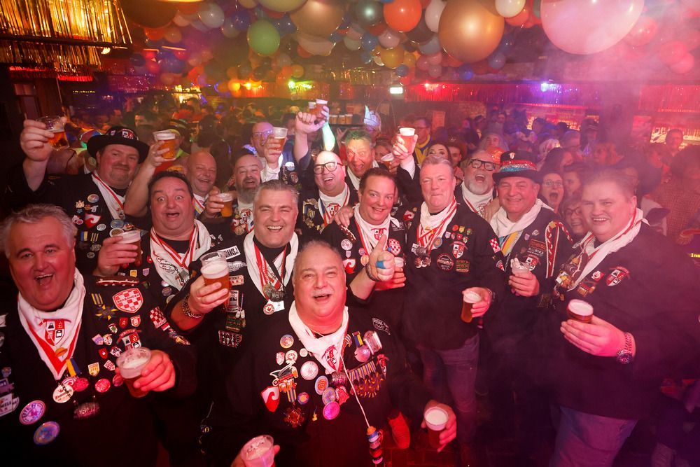 Een groep mensen staat in een kamer met drankjes in de hand.