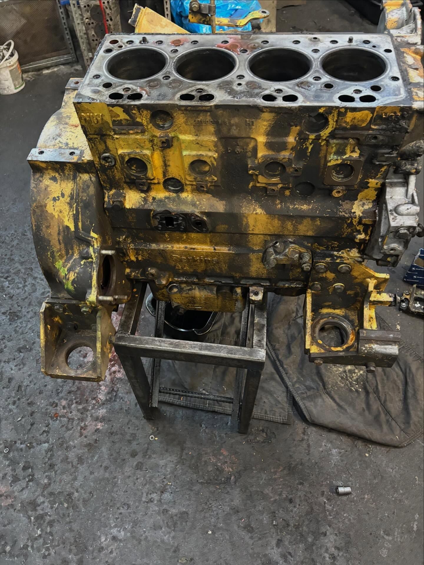 Blocco motore giallo in un'officina, appoggiato su un supporto metallico.