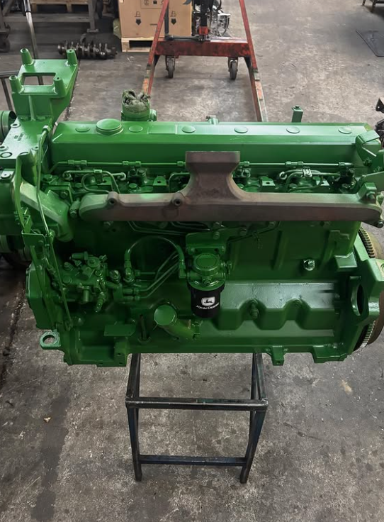 Motore John Deere, verde, montato su supporto nero, in un'officina.