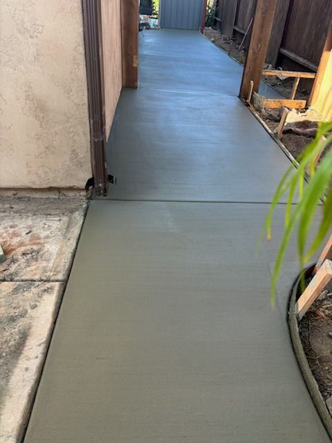 A concrete walkway is being built next to a fence.