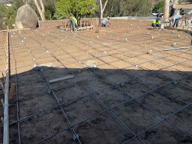 A group of construction workers are working on a concrete floor.