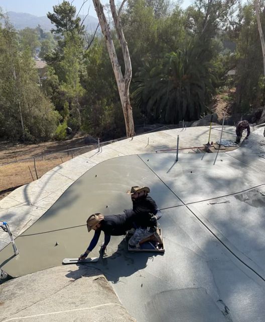 A person laying on a concrete surface with trees in the background