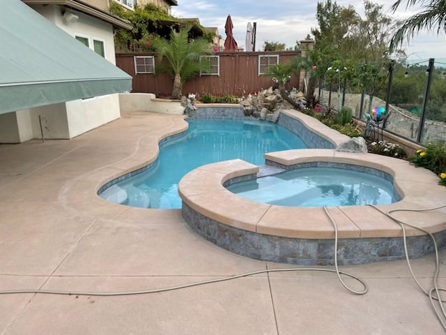 A large swimming pool with a hot tub in the middle of it.