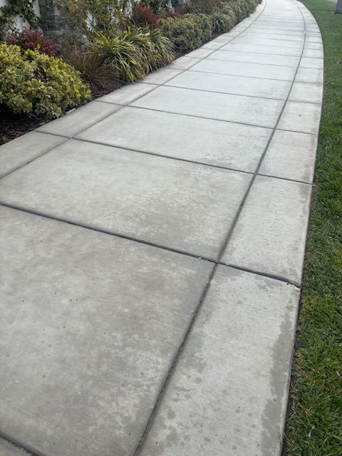 A concrete walkway going through a lush green field.