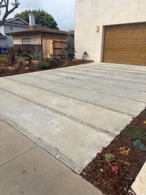 A concrete driveway in front of a house with a wooden garage door