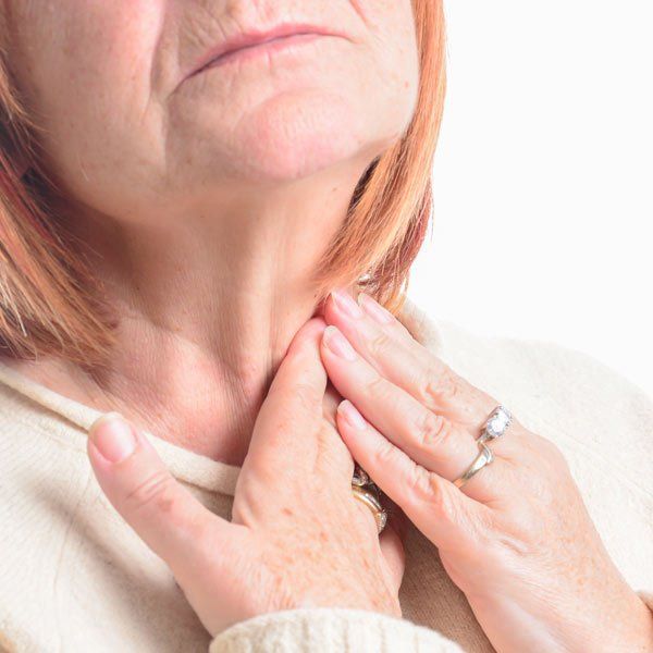 Woman rubbing her throat from Hashimoto's Disease discomfort