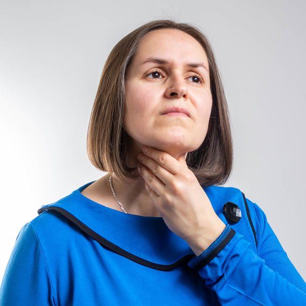Woman with Hashimoto's Thyroiditis rubbing her throat