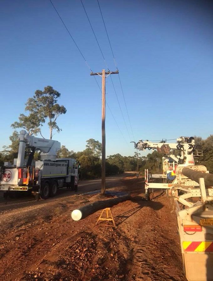 A Crane is Working on a Power Line on a Dirt Road — Country Powerline Constructions in Dubbo, NSW