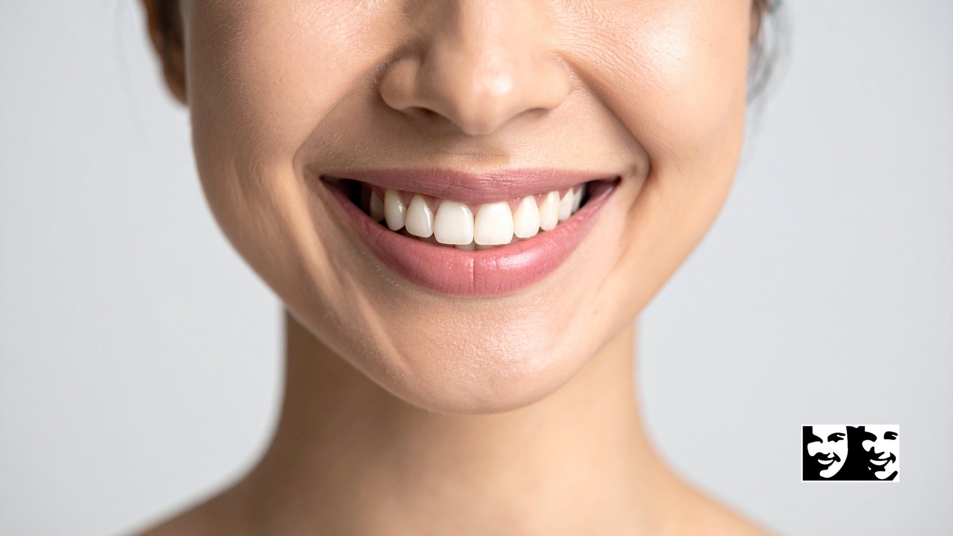 Close-up of a person's mouth, showing slightly discolored teeth and a mole on the chin.