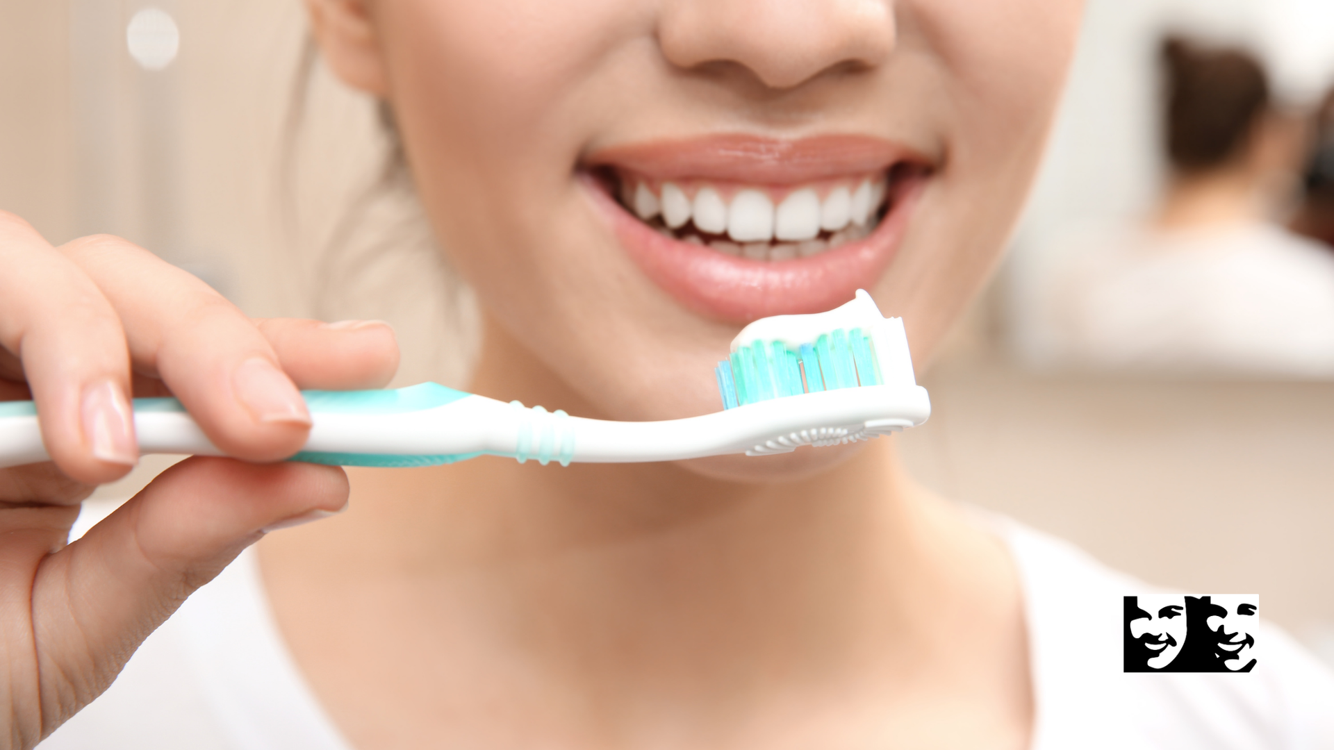Woman smiling, holding toothbrush with toothpaste, ready to brush her teeth.