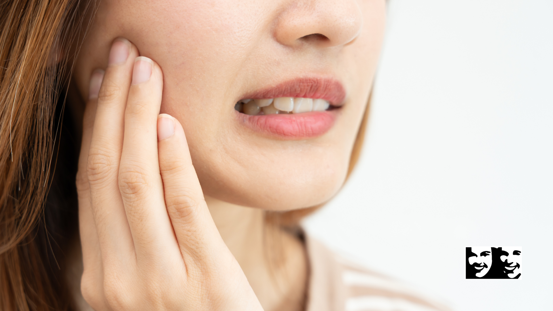 Woman holding face in pain, eyes closed, white tank top, light background.