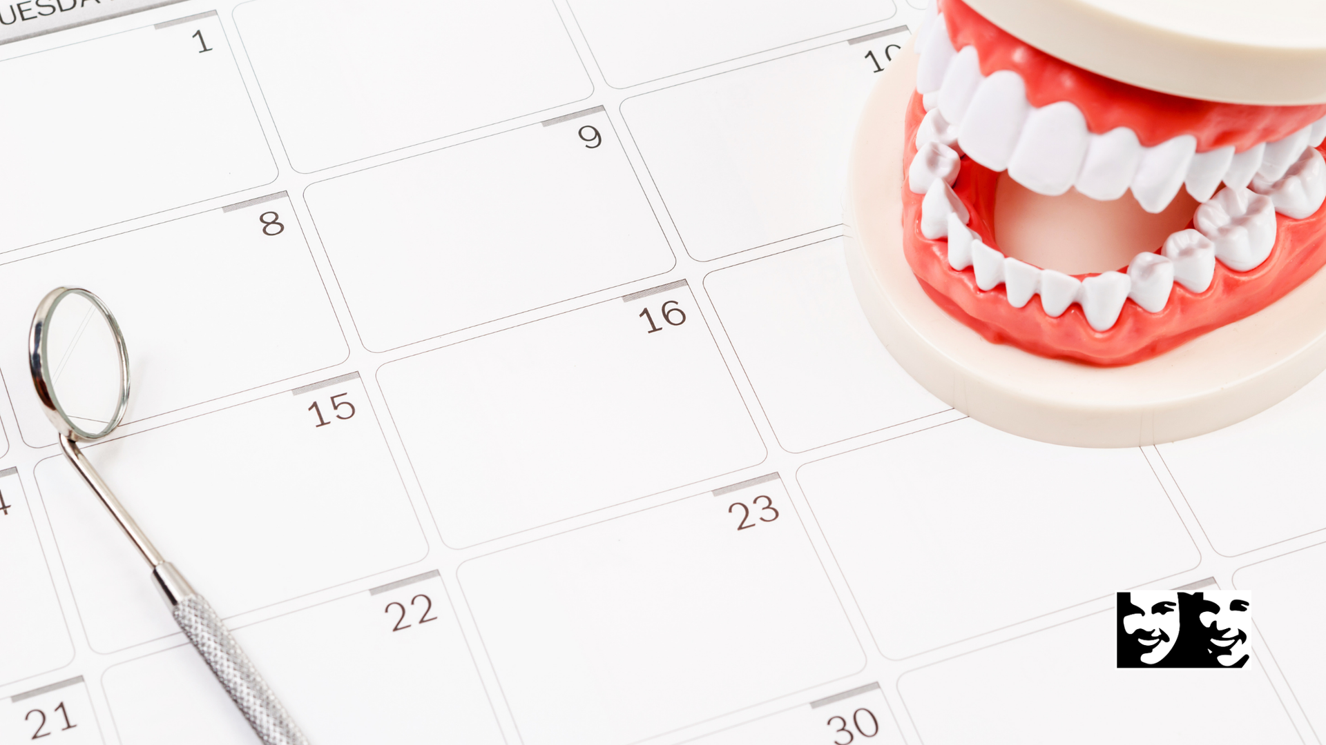 A dental model is sitting on top of a calendar next to a dental mirror.