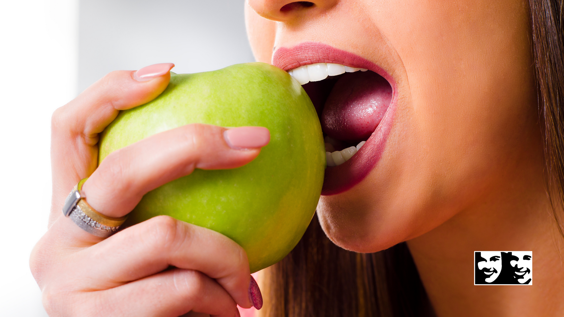 A woman is eating a green apple with her mouth open