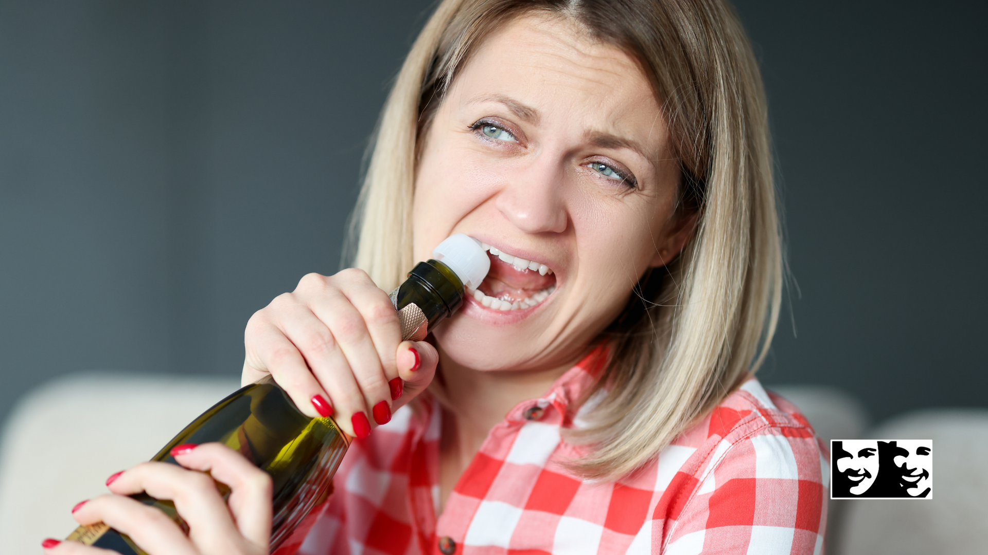 A woman is holding a bottle of wine in her mouth.