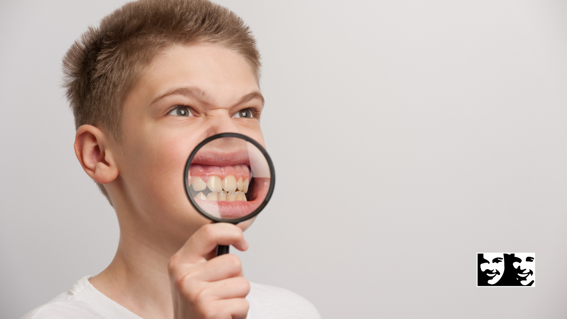 Boy with a magnifying glass examining his teeth.