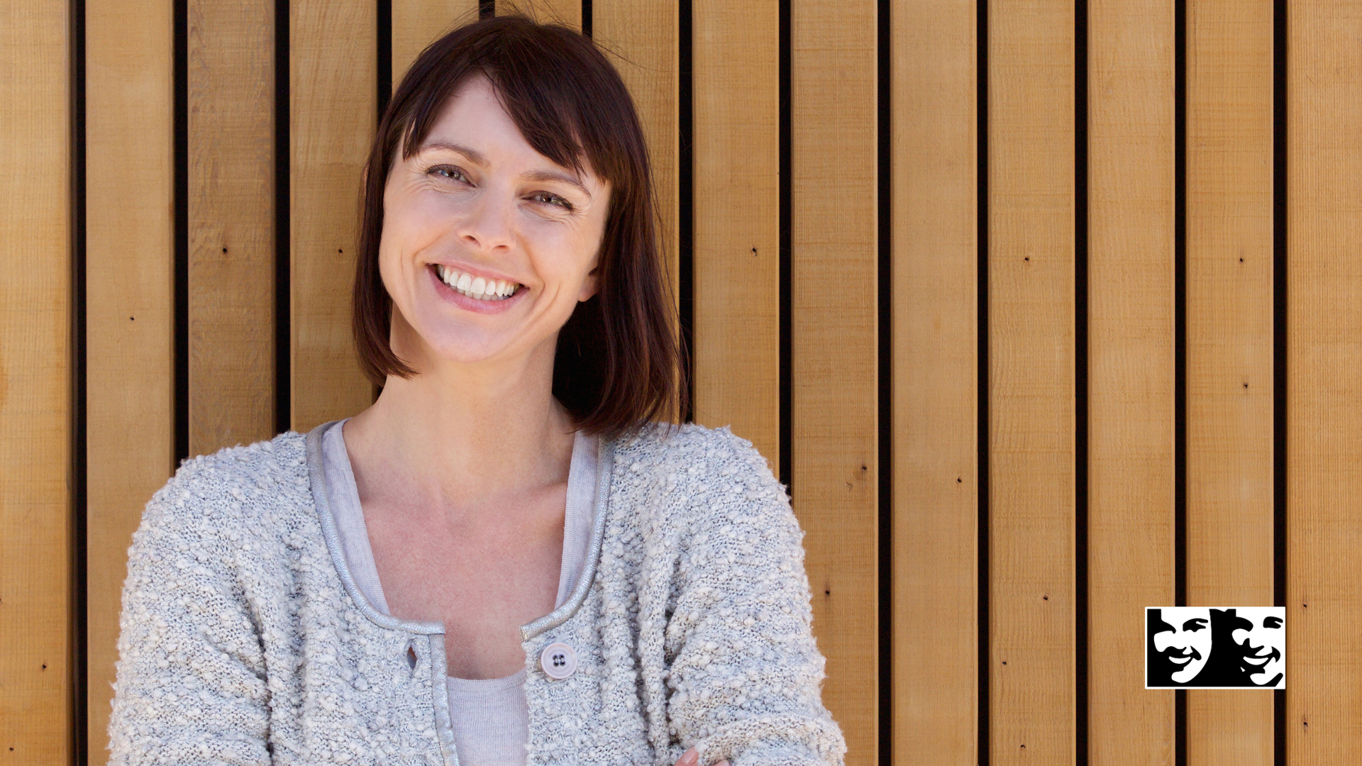 Woman smiling in front of a wood-paneled wall.