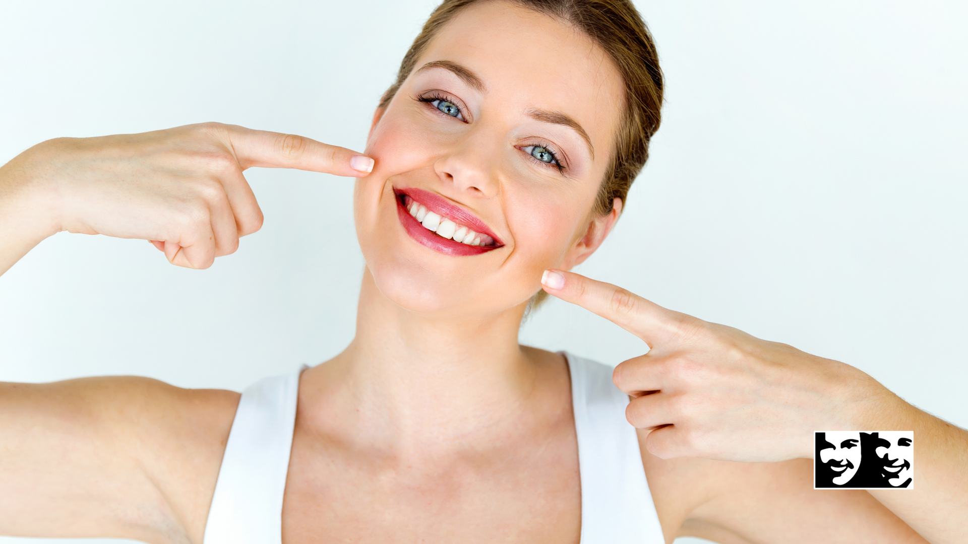 A woman is smiling and pointing at her teeth.