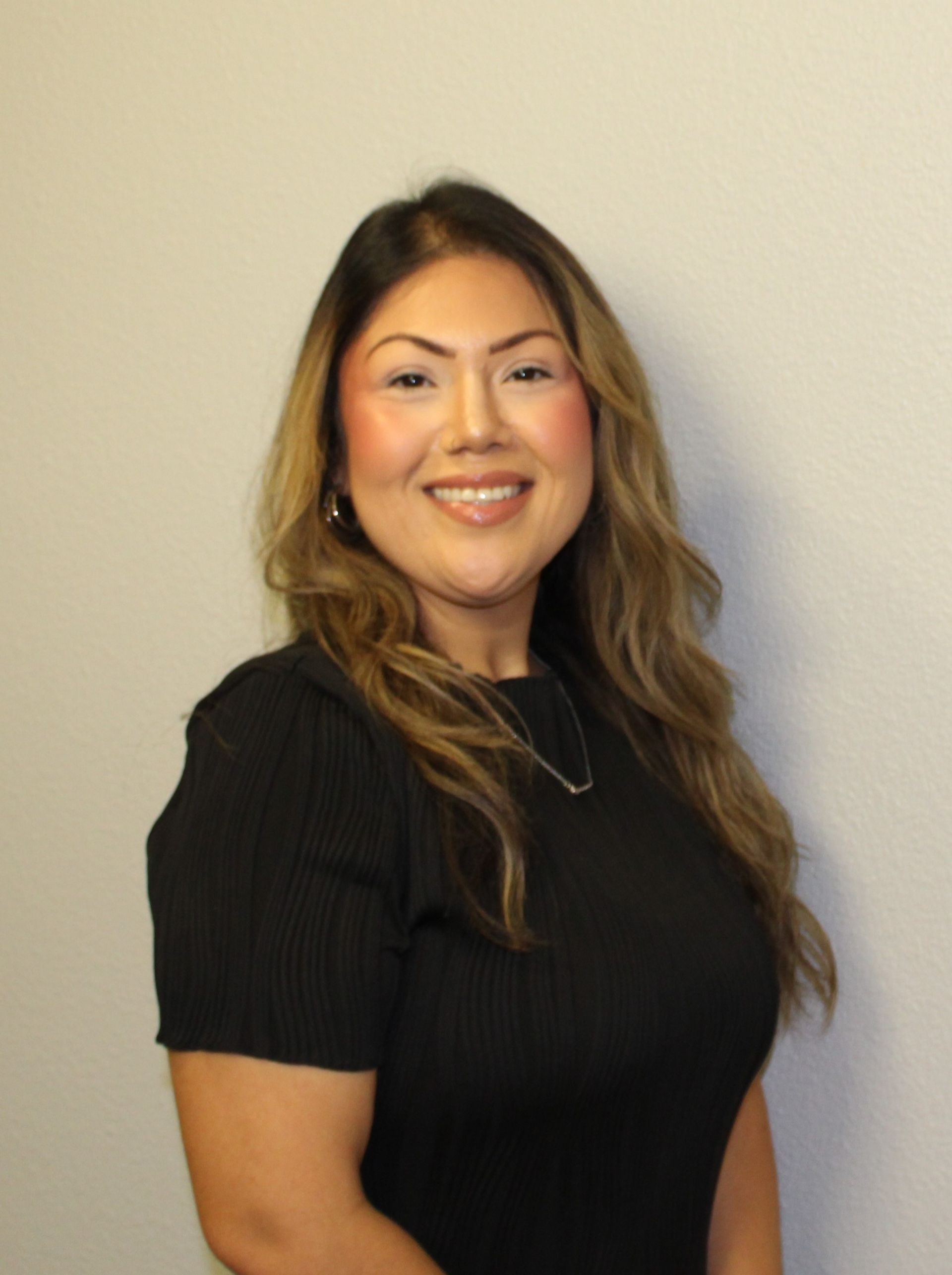 A woman in a black shirt is smiling for the camera.