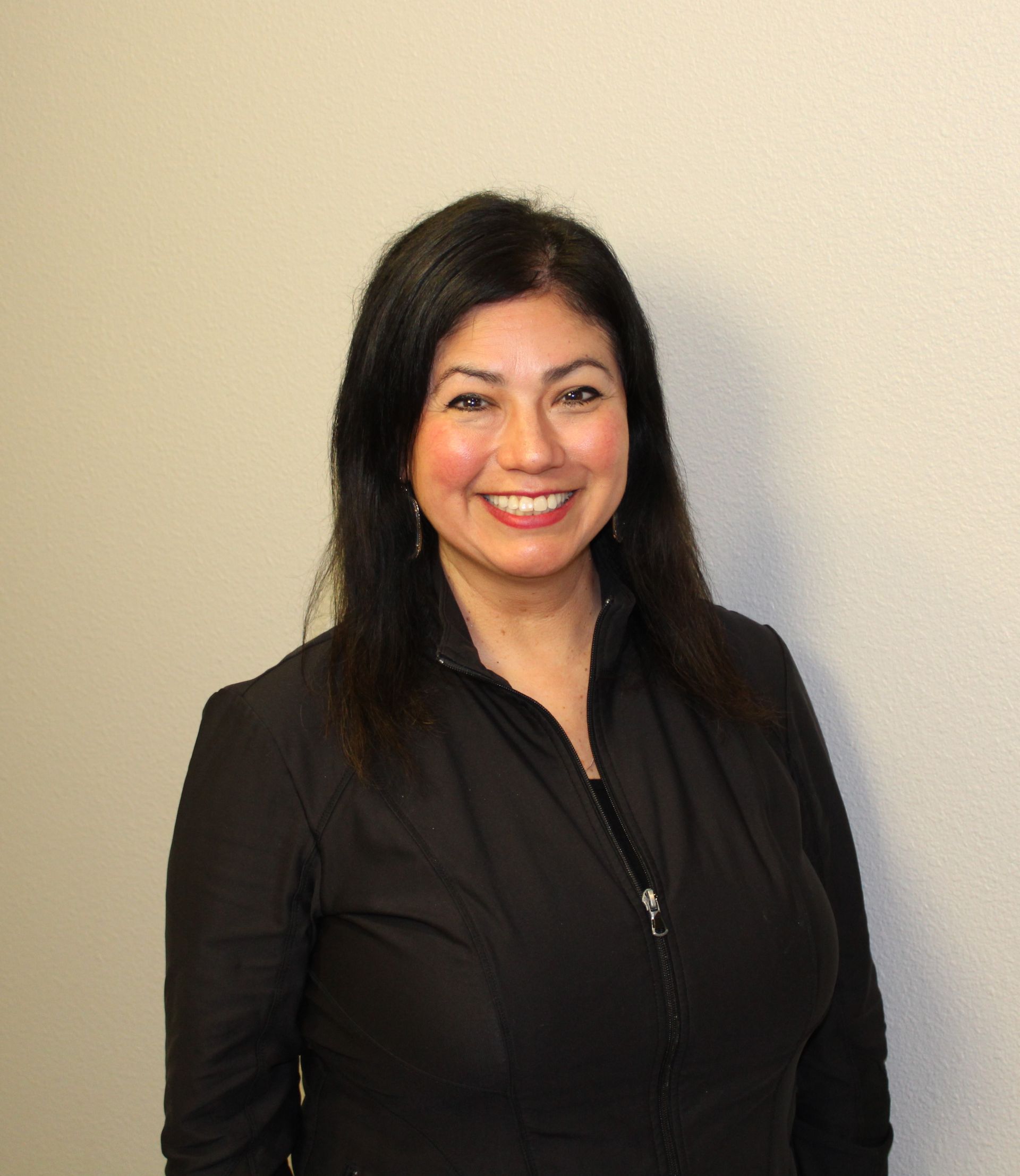 A woman in a black jacket is smiling for the camera