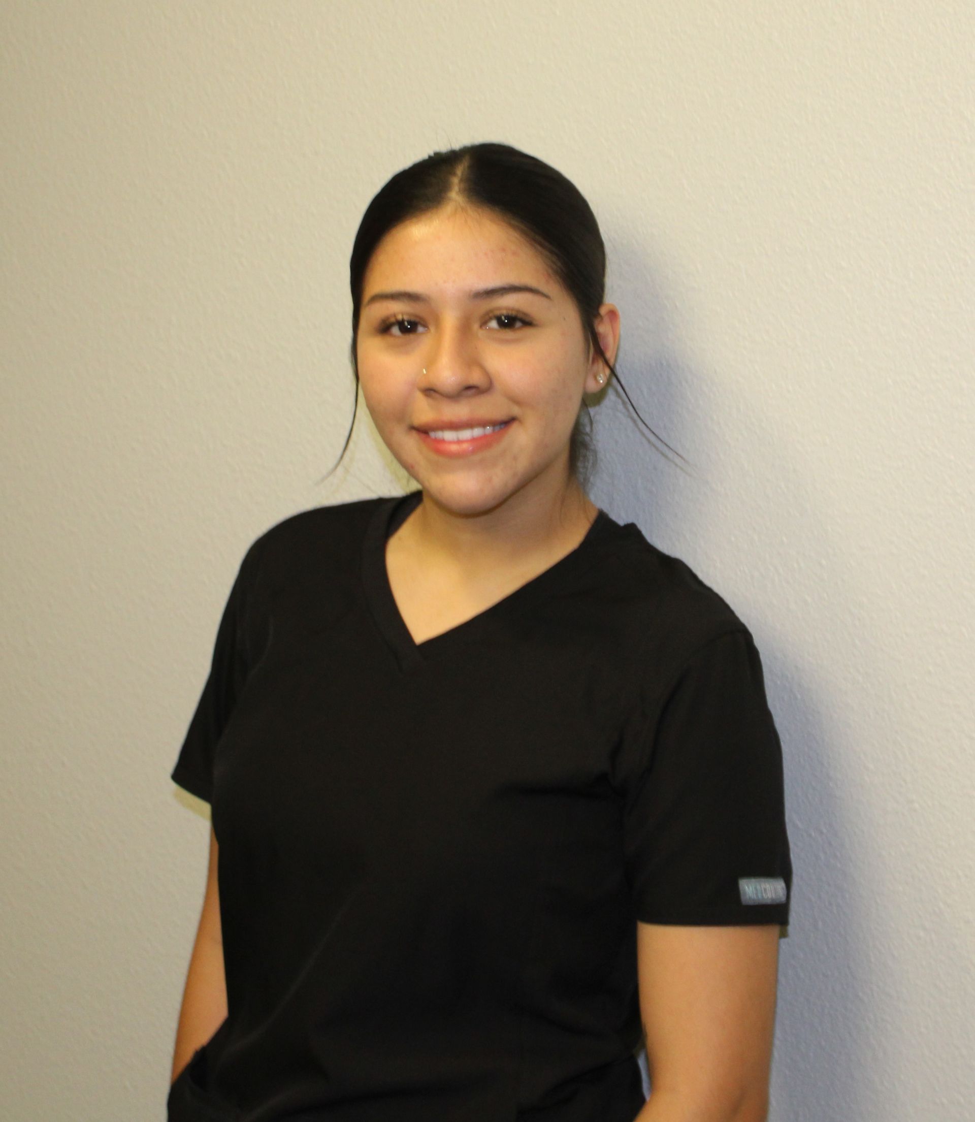 A woman in a black scrub top is smiling for the camera