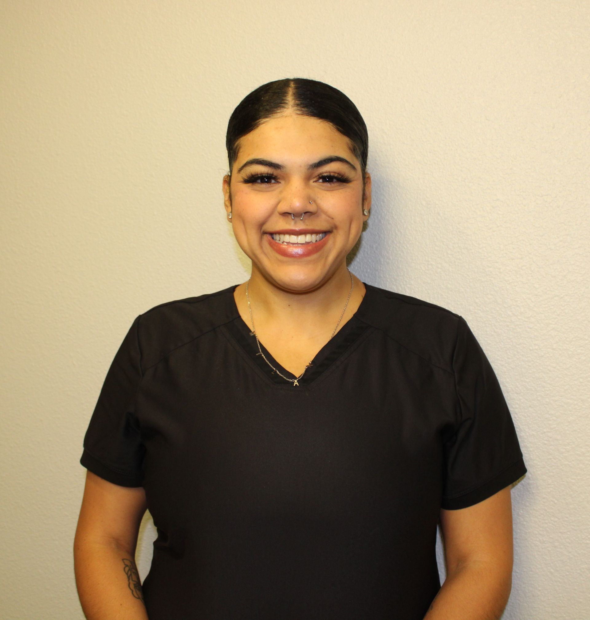 A woman in a black scrub top is smiling for the camera
