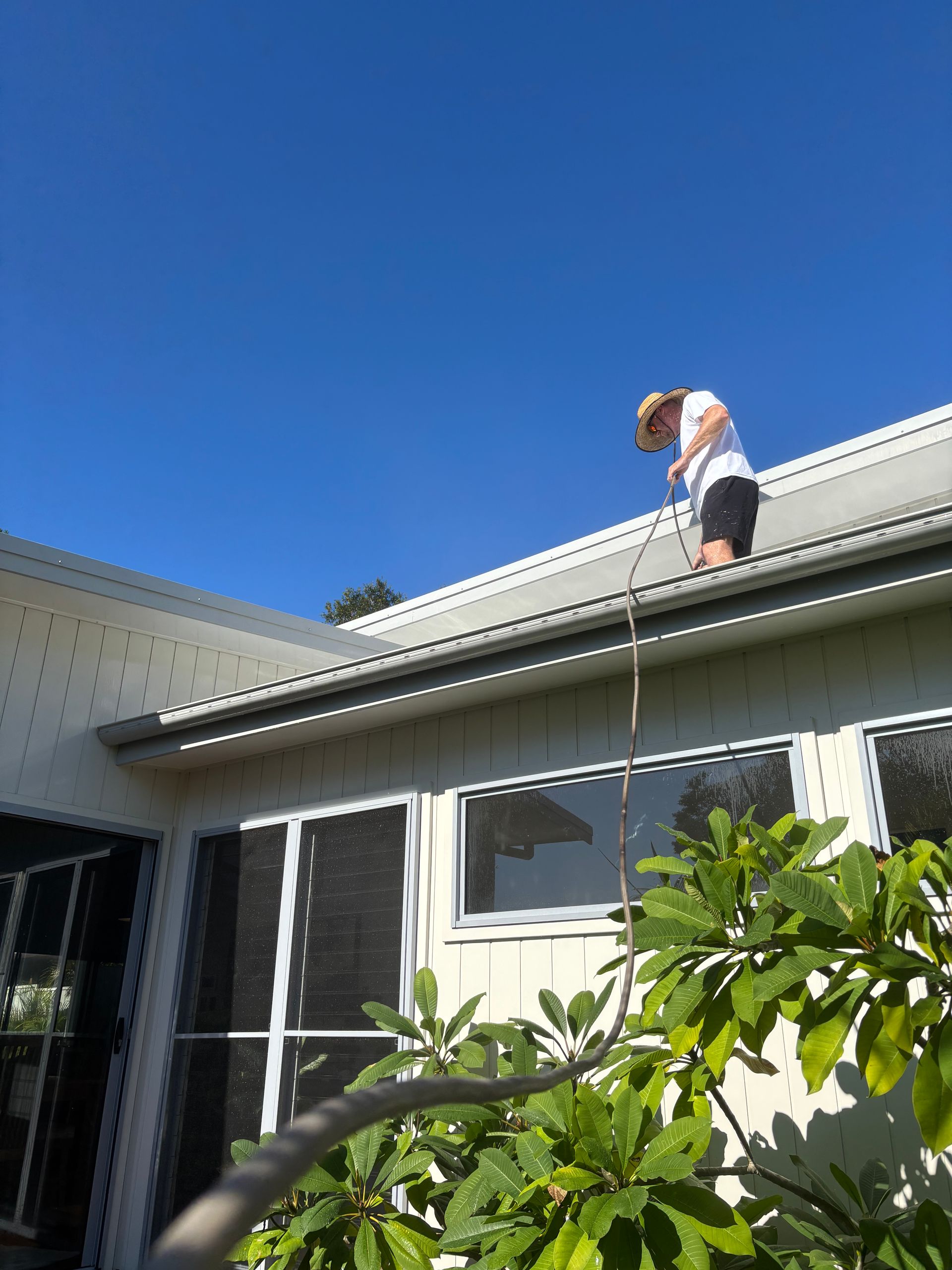 A person is standing on the roof of a house — Timeless Painting In Umina Beach, NSW