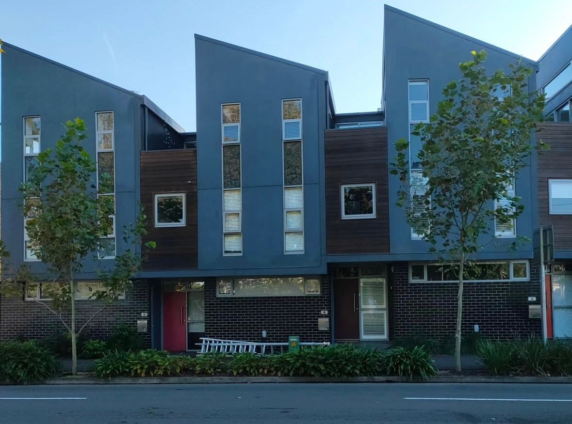 A row of blue buildings with square windows and a red door — Timeless Painting In Umina Beach, NSW