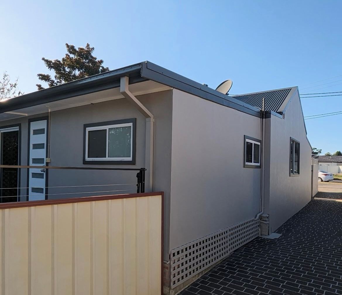 A house with a fence in front of it and a blue sky in the background — Timeless Painting In Umina Beach, NSW