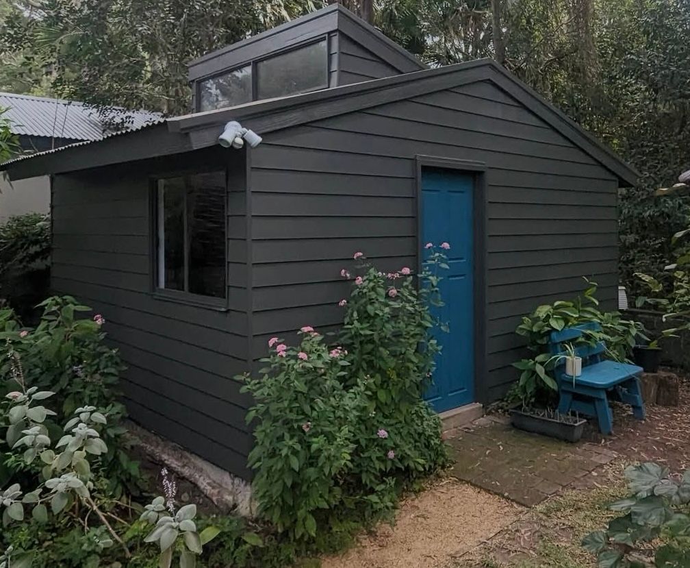A small shed with a blue door and a chair in front of it — Timeless Painting In Umina Beach, NSW