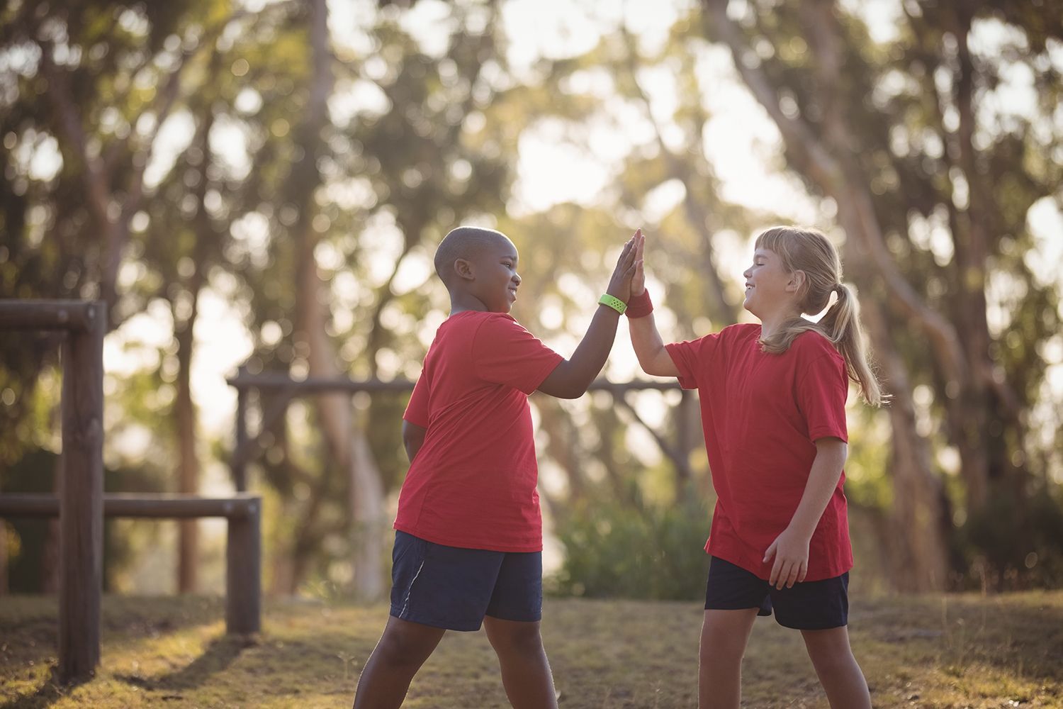 Happy kids giving high fives in a summer camp.