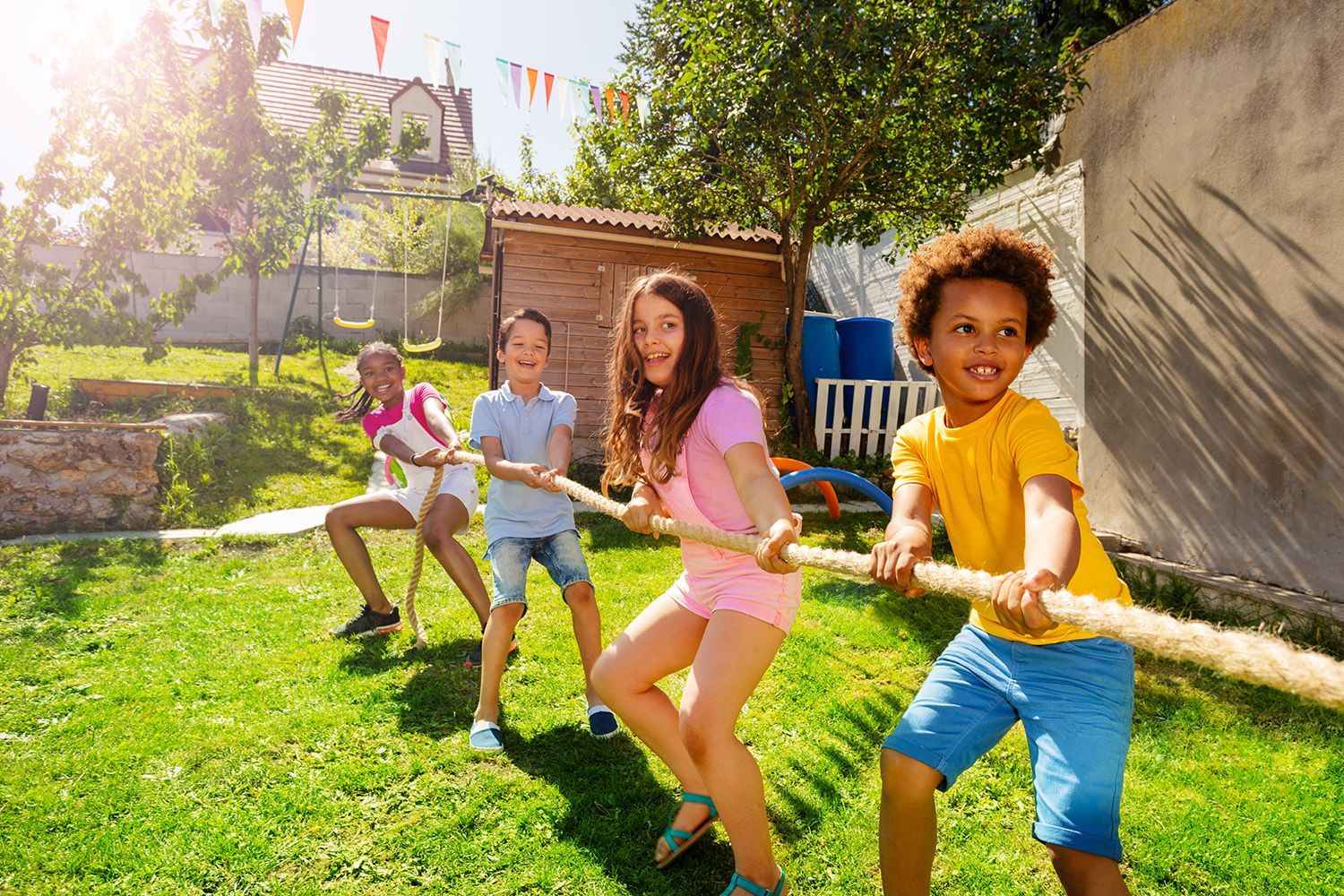 A group of kids play a rope-pulling game on the lawn.