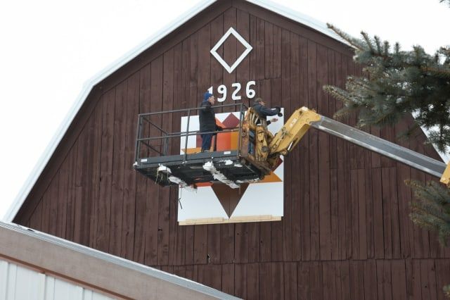 Electrician on Cherry Picker Truck Fixing Signage — Shawano, WI — Raddant Electric Service Inc