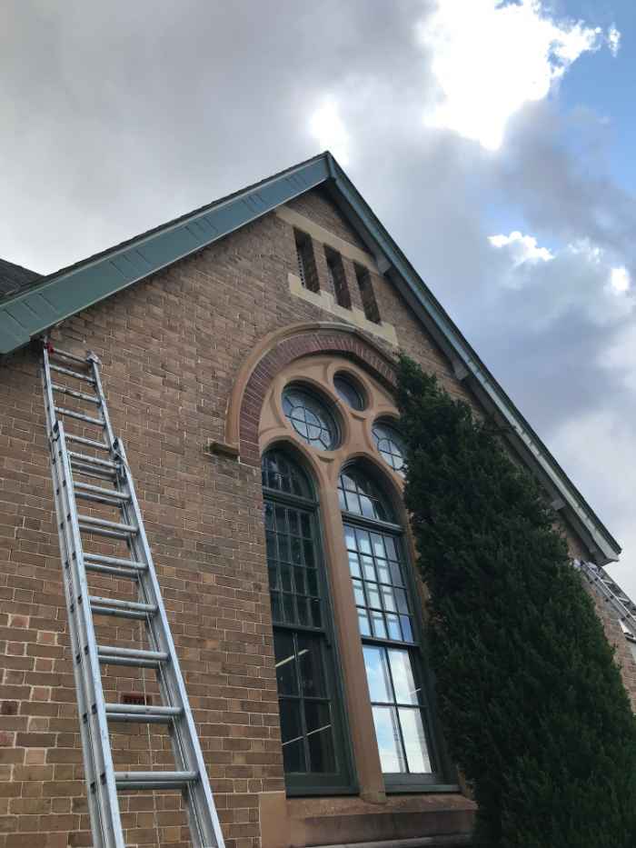 long ladder resting against a brick wall