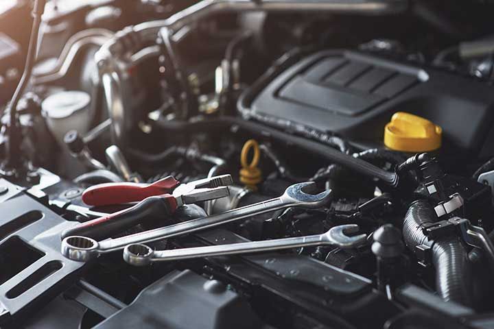 Mechanic hand checking and fixing a broken car in car service garage 
