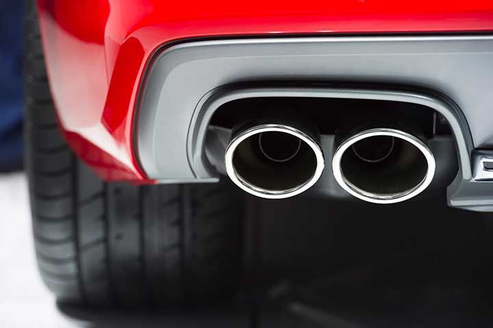 Chrome exhaust pipe of red powerful sport car bumper 

