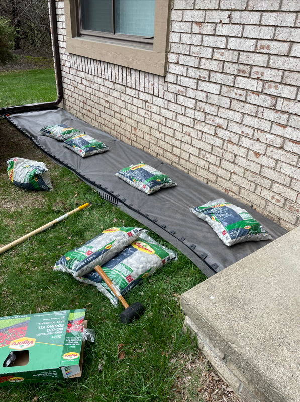A bunch of bags of dirt are sitting on the ground in front of a brick building.