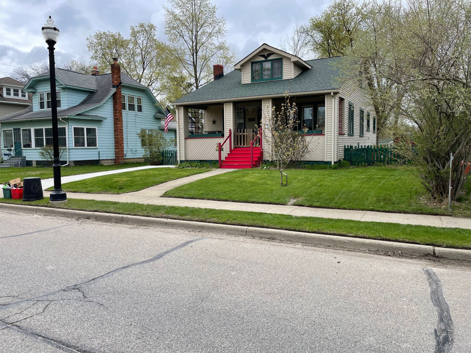 A house with a red staircase is sitting on the side of the road next to a street light.