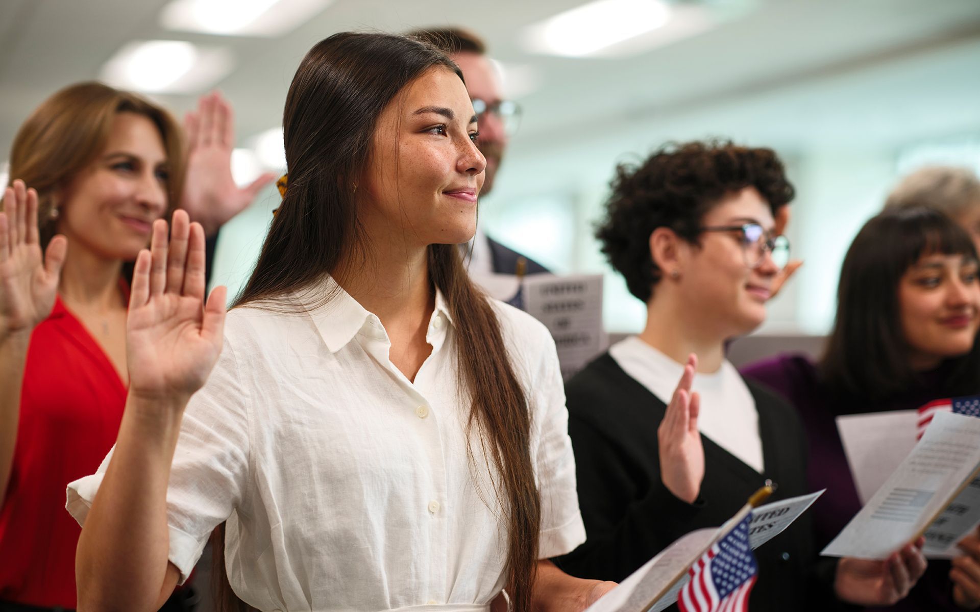 A group of people are waving their hands in the air at a citizenship ceremony.