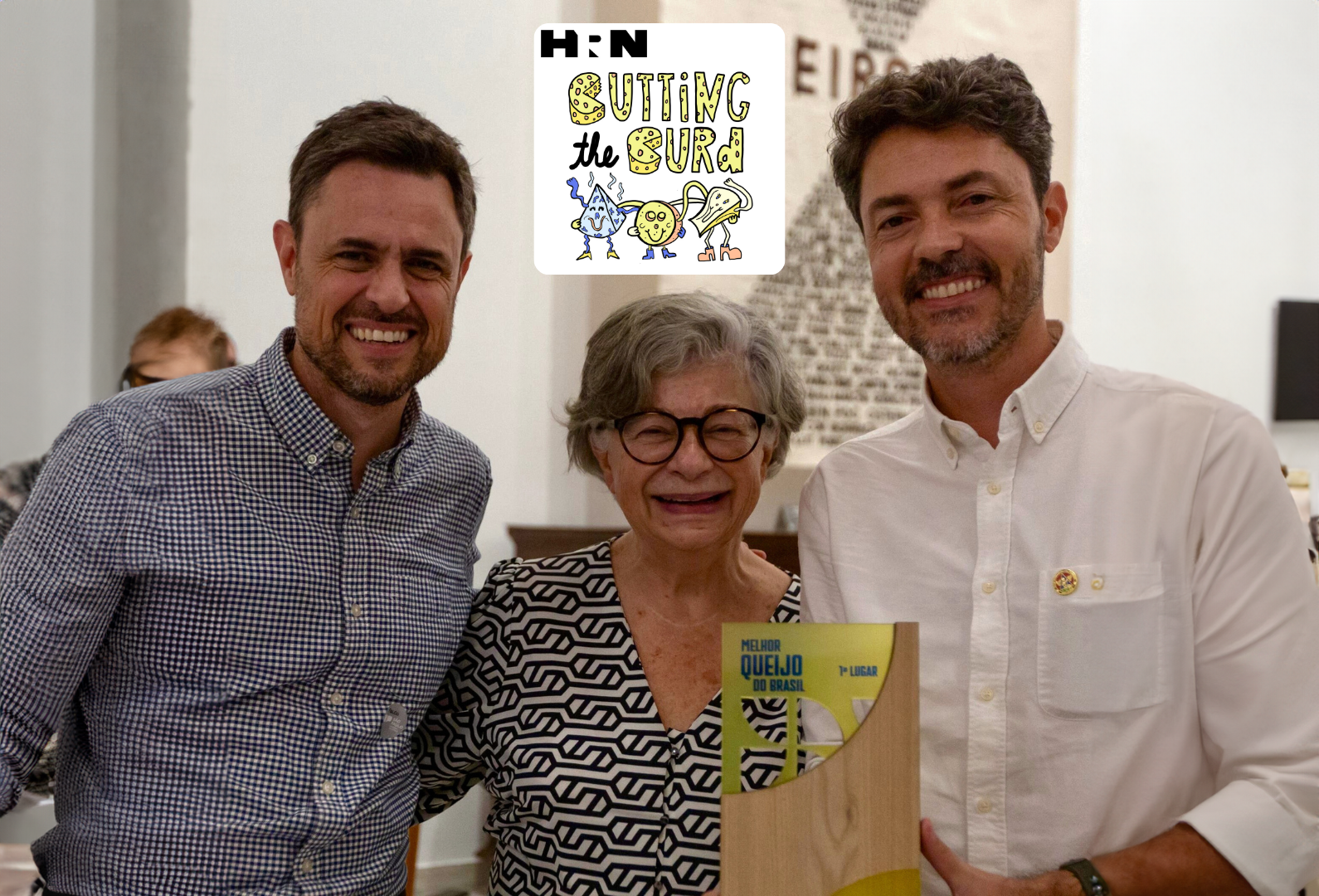 Dois homens e uma mulher estão posando para uma foto com um logotipo hn ao fundo