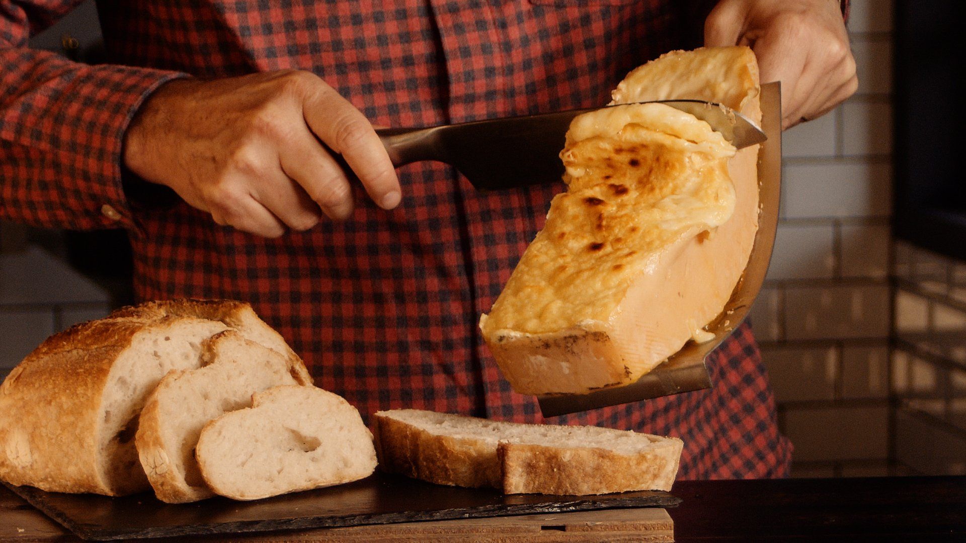 Um homem está cortando um pão em uma tábua de corte.