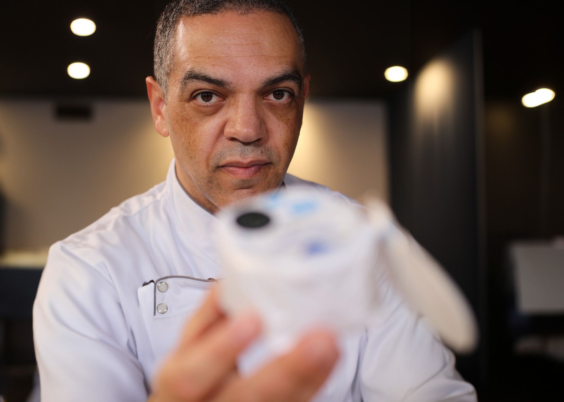 Um homem de camisa branca segura um objeto branco na mão