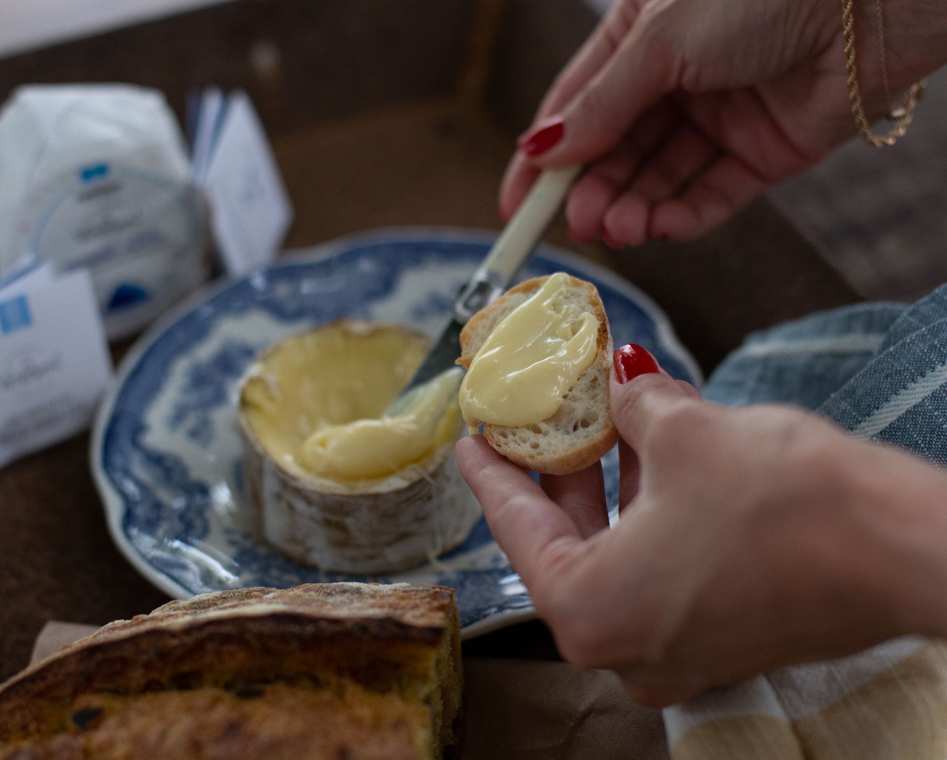 Uma pessoa está espalhando queijo em um pedaço de pão.