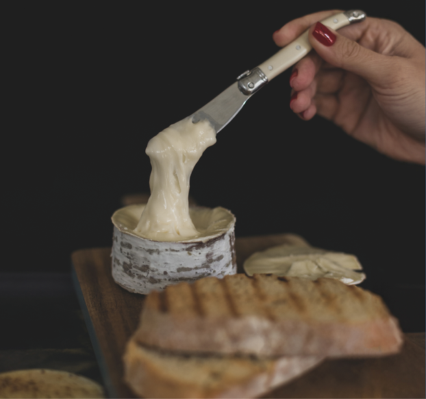 Uma pessoa está espalhando queijo em um sanduíche grelhado